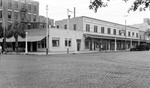 Brick street with clothing store, Palm Book Shop, Peacock Row, Williams Art Store, cars, benches by Francis G. Wagner and Nelson Poynter Memorial Library