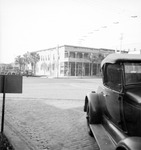 Beverly Hotel across the street; car with background of two-story building, row of parked cars, man standing in distance, corner of Central Avenue and 4th Street