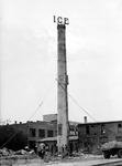 Ice company smokestack, buildings (one says Storage), men working, truck, materials. Sign on smokestack says Darden Haley, Campbell Hardware Company, and Norge by Francis G. Wagner and Nelson Poynter Memorial Library