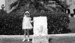 Girl standing next to a float with several dolls and a sign, "Happy Days Are Here Again for My Little Sunshine Dollies."; taken at Vinoy Hotel by Francis G. Wagner and Nelson Poynter Memorial Library