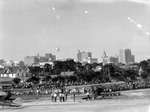 Goodyear Blimp flying over downtown St. Petersburg, including the Times building, Princess Martha, Central National Bank and Trust Co., and other tall buildings.; Airport Lunch, crowd of people and parked planes in foreground by Francis G. Wagner and Nelson Poynter Memorial Library