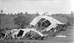 Dirigible wreck on the ground in an open field, cars parked, people nearby, a man with a rifle on his shoulder guarding wreckage by Francis G. Wagner and Nelson Poynter Memorial Library