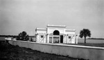 Decorative bathhouse with door on each side of arched entrance leading to water; low wall with flowerpots, foliage, land in background. Envelope said this was at Tierra Verde by Francis G. Wagner and Nelson Poynter Memorial Library