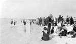 Closer view of people at beach near water's edge, buildings farther away in background, Wagner family in foreground: Dick and Francis standing and looking down away from water, Bud making sand castle, Mattie with glasses and necklace by Francis G. Wagner and Nelson Poynter Memorial Library