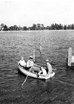 Four people near dock embarking on a rowboat trip, land in background by Francis G. Wagner and Nelson Poynter Memorial Library