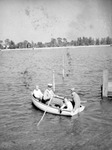 Four people near a dock embarking on a rowboat trip, land in background by Francis G. Wagner and Nelson Poynter Memorial Library