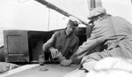 Francis and unknown man (back to camera) drinking shots on sailboat by Francis G. Wagner and Nelson Poynter Memorial Library
