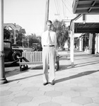 Francis standing at Brantley Building on 2nd Street North in front of bench, parked cars, camera shop by Francis G. Wagner and Nelson Poynter Memorial Library