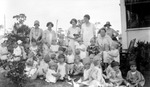 Group of children wearing hats with some women in yard, others looking out of window. Date: 1920s? by Francis G. Wagner and Nelson Poynter Memorial Library