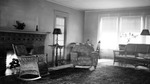 Interior: 556 19th Avenue NE. Square brick fireplace, candlestick, lamps on tables, overstuffed flowered chair, wicker sofa, wicker chair, flowered carpet, windows, telephone by Francis G. Wagner and Nelson Poynter Memorial Library