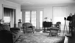 Interior: 556 19th Avenue NE. French doors, overstuffed flowered chair, flowered sofa, flowered carpet, wicker chair, lamp and statue on cabinet, window, small ornate table, photographic flash light on tripod by Francis G. Wagner and Nelson Poynter Memorial Library
