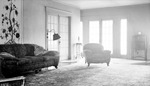 Interior: 556 19th Avenue NE. French doors, overstuffed flowered chair, flowered sofa, flowered carpet, flowered wall hanging, part of wicker chair, floor lamp, clock on tall cabinet, small ornate table with statue by Francis G. Wagner and Nelson Poynter Memorial Library