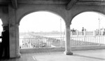 Loggia at Million Dollar Pier: man in suit leaning against wall, people standing outside, many cars and people on pier approach; looking west by Francis G. Wagner and Nelson Poynter Memorial Library