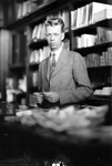 Portrait of Francis without a hat in front of bookshelves by Francis G. Wagner and Nelson Poynter Memorial Library