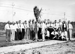 Large group of men planting a tree by side of road by Francis G. Wagner and Nelson Poynter Memorial Library