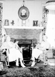 Interior: Two older women seated in wicker chairs reading in front of fireplace; drapes, clock, several portraits by Francis G. Wagner and Nelson Poynter Memorial Library