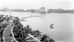 Looking northeast on Flagler Drive in West Palm Beach toward Palm Beach; cars, boat in Intracoastal, Flagler Hotel, Royal Poinciana, water tower, Biltmore, Breakers by Francis G. Wagner and Nelson Poynter Memorial Library