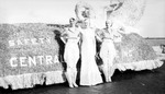 Three women posed next to a parade float by Francis G. Wagner and Nelson Poynter Memorial Library
