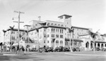 Unknown large elaborate building, four or more stories, with courtyard. Possibly a non-local hotel. Parked cars, palm trees, telephone poles by Francis G. Wagner and Nelson Poynter Memorial Library