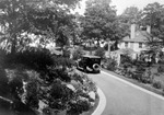 Unknown house. car driving on paved street past large two-story house with two chimneys, trees and foliage all around by Francis G. Wagner and Nelson Poynter Memorial Library