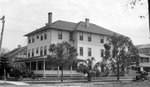 Unknown house, large three-story house with wraparound porch, multiple chimneys, low brick wall, trees and palm tree, parked car by Francis G. Wagner and Nelson Poynter Memorial Library